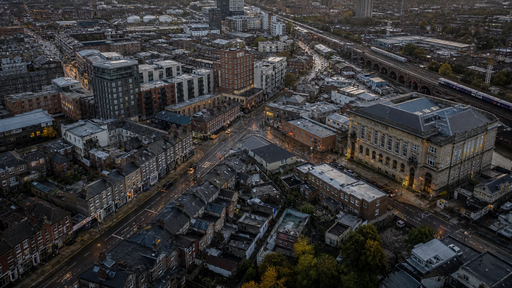 Aerial view of a UK district containing homes, commercial buildings, rail infrastructure, and civic property.